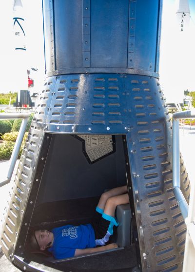 Kenny piloting the one-seat Mercury Capsule mockup in the rocket garden at Kennedy Space Center.